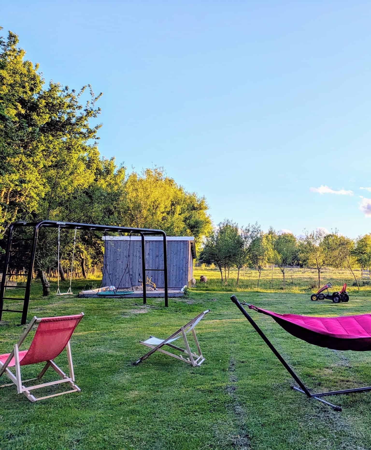 Farm grounds with a hammock, lounge chairs, and swings among fruit trees