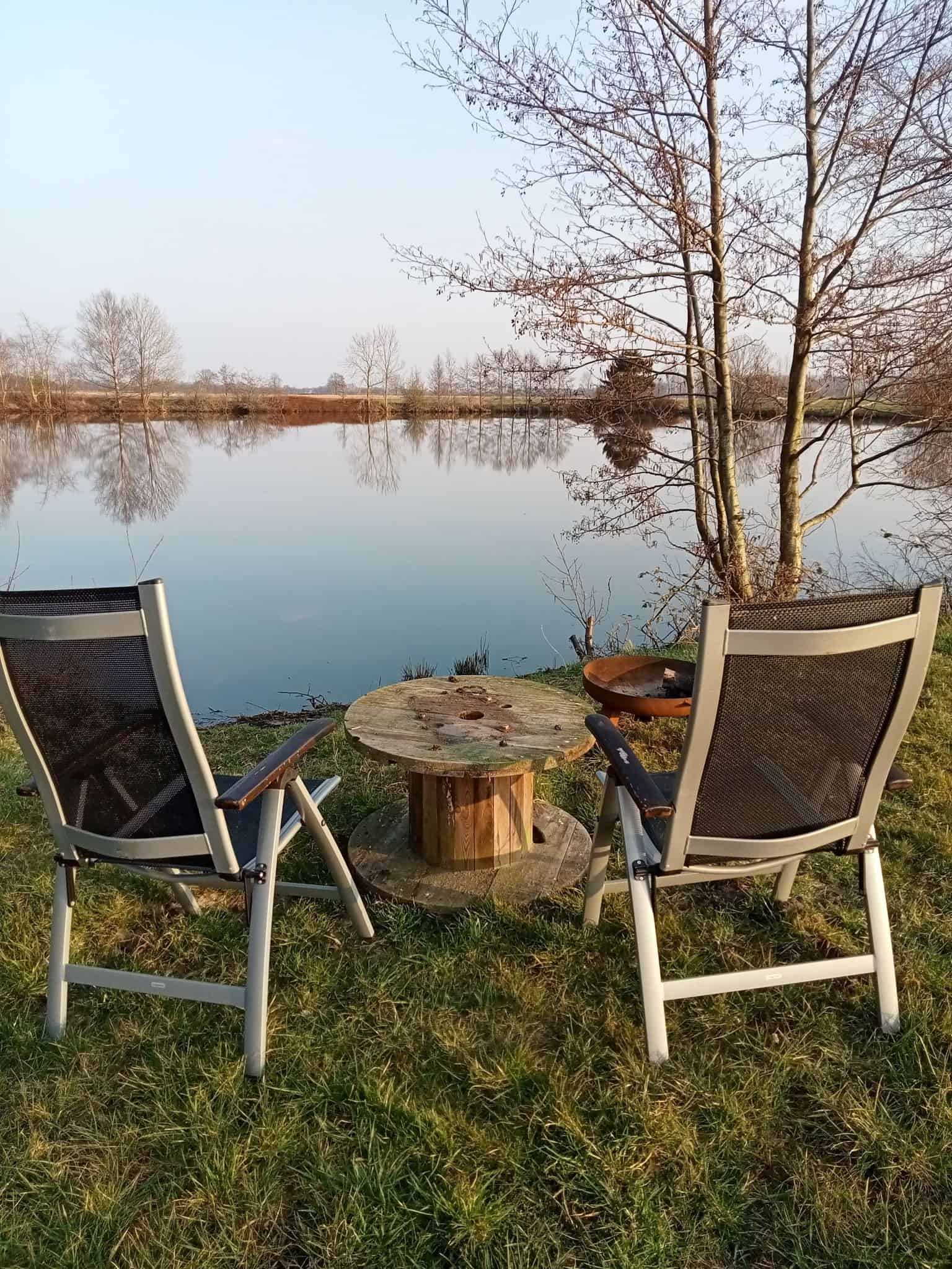 Two chairs beside the calm water of the farm's natural pond