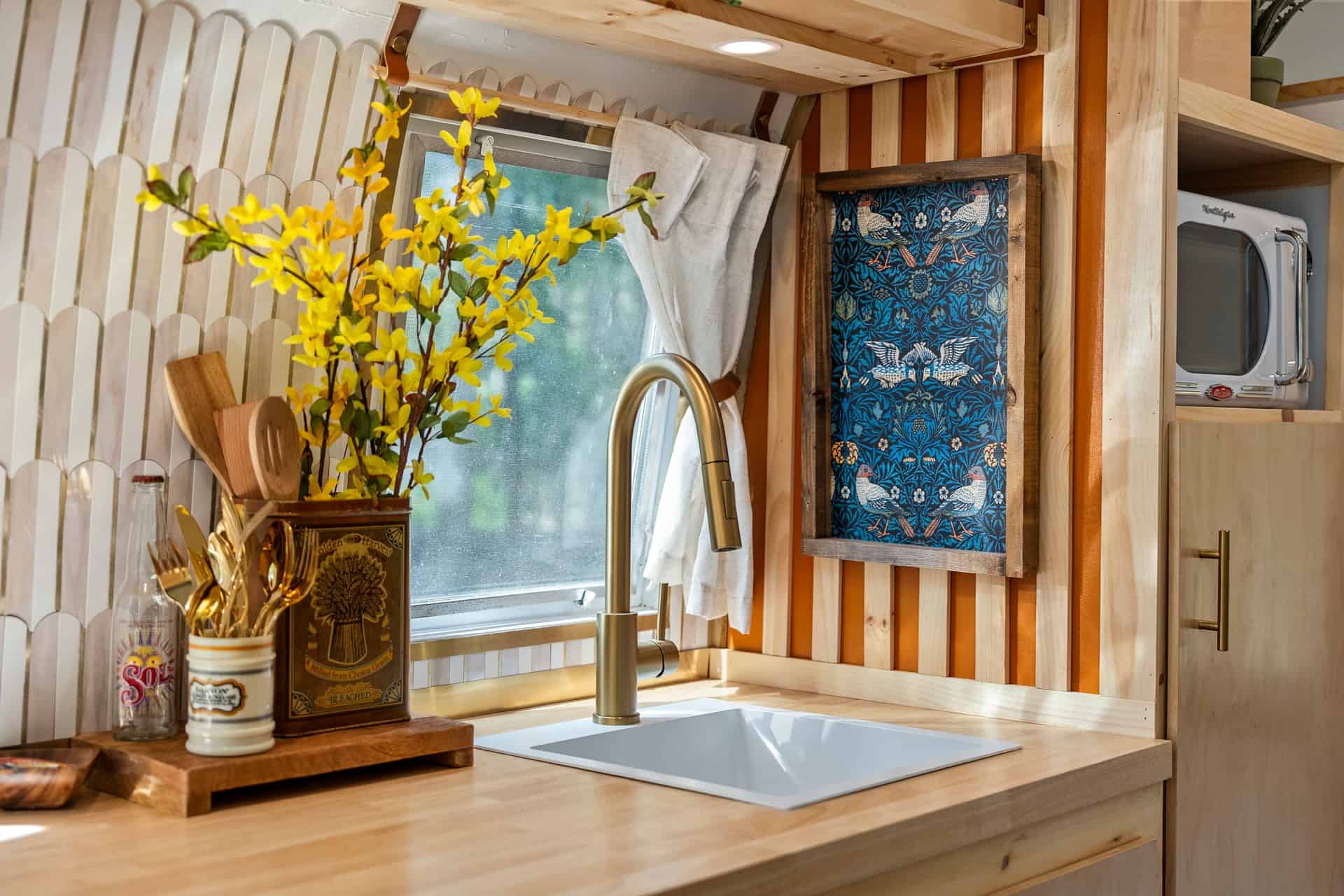 Butcher-block kitchen counter with a square white sink, gold gooseneck faucet, picket tile, and a Nostalgia microwave in a wood cubby