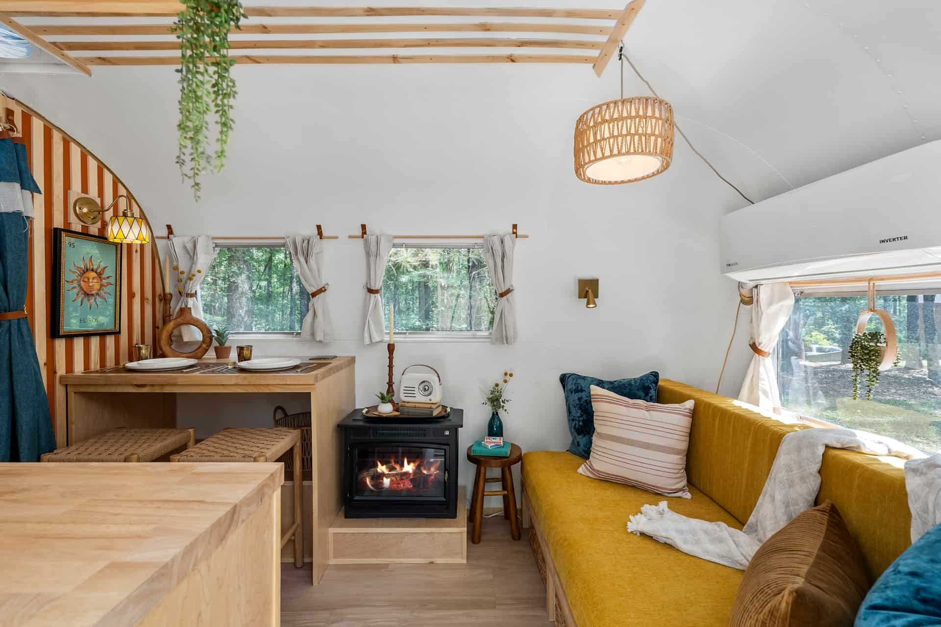 Interior of Sol with a mustard custom couch, dining bar with two stools, black electric fireplace, and a white mini-split over the window