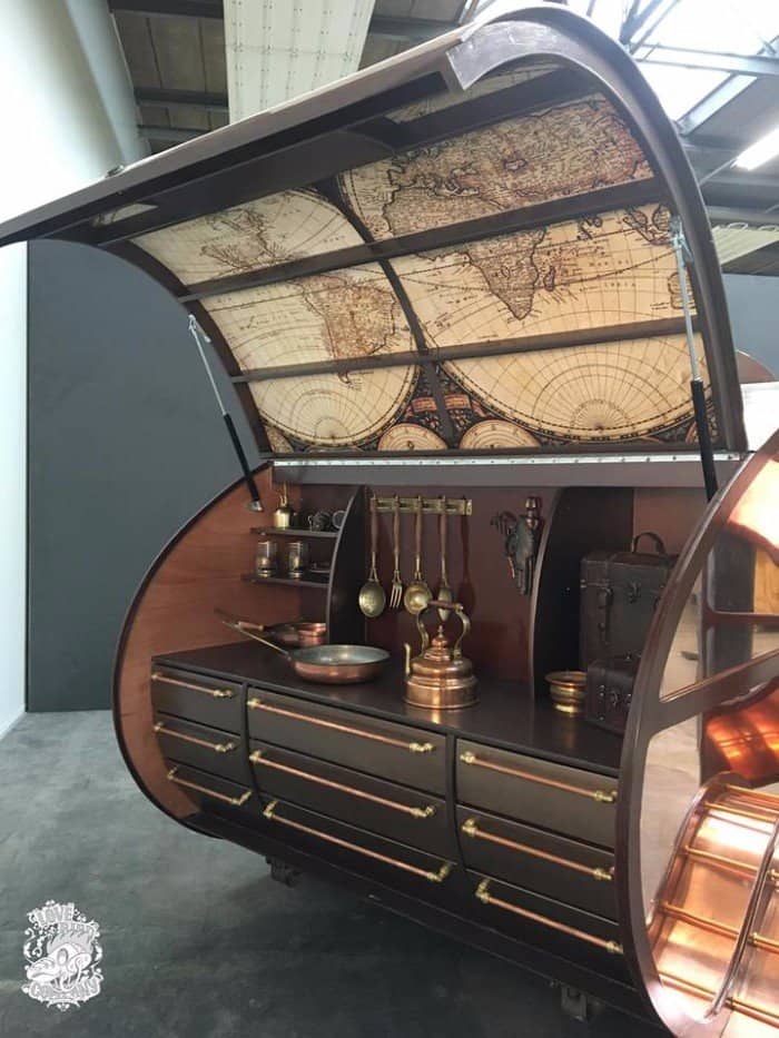 Open galley with an antique world-map hatch lining, copper kettle, brass utensils, and copper-handled drawers