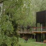 Two two-level black Studzienno 27 cabins among birch trees, with green window bays, balconies, and deck tables
