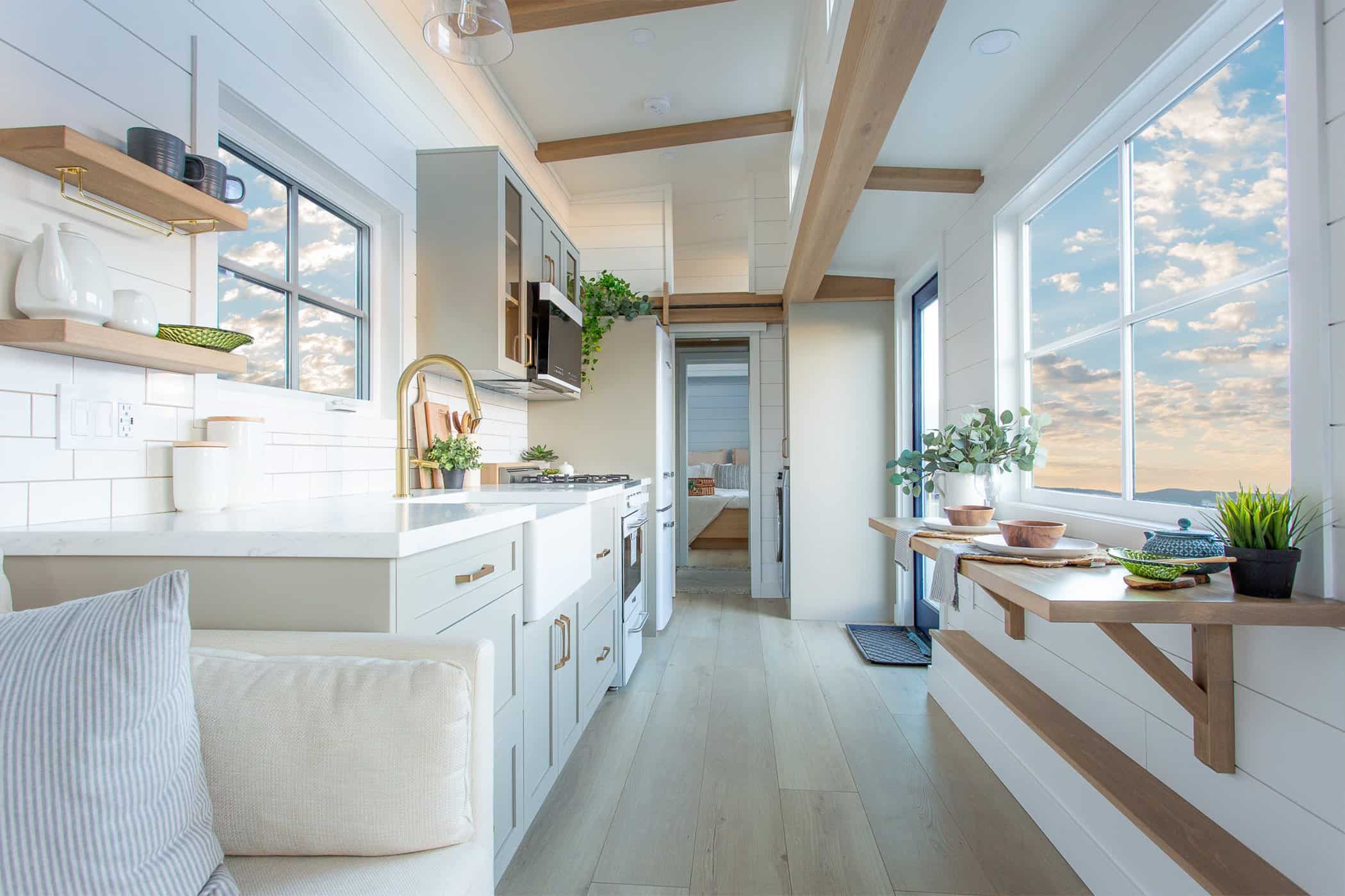 Summit Boho full galley: sage-green cabinets, farmhouse sink, gold faucet, floating wood breakfast bar under the window, white shiplap