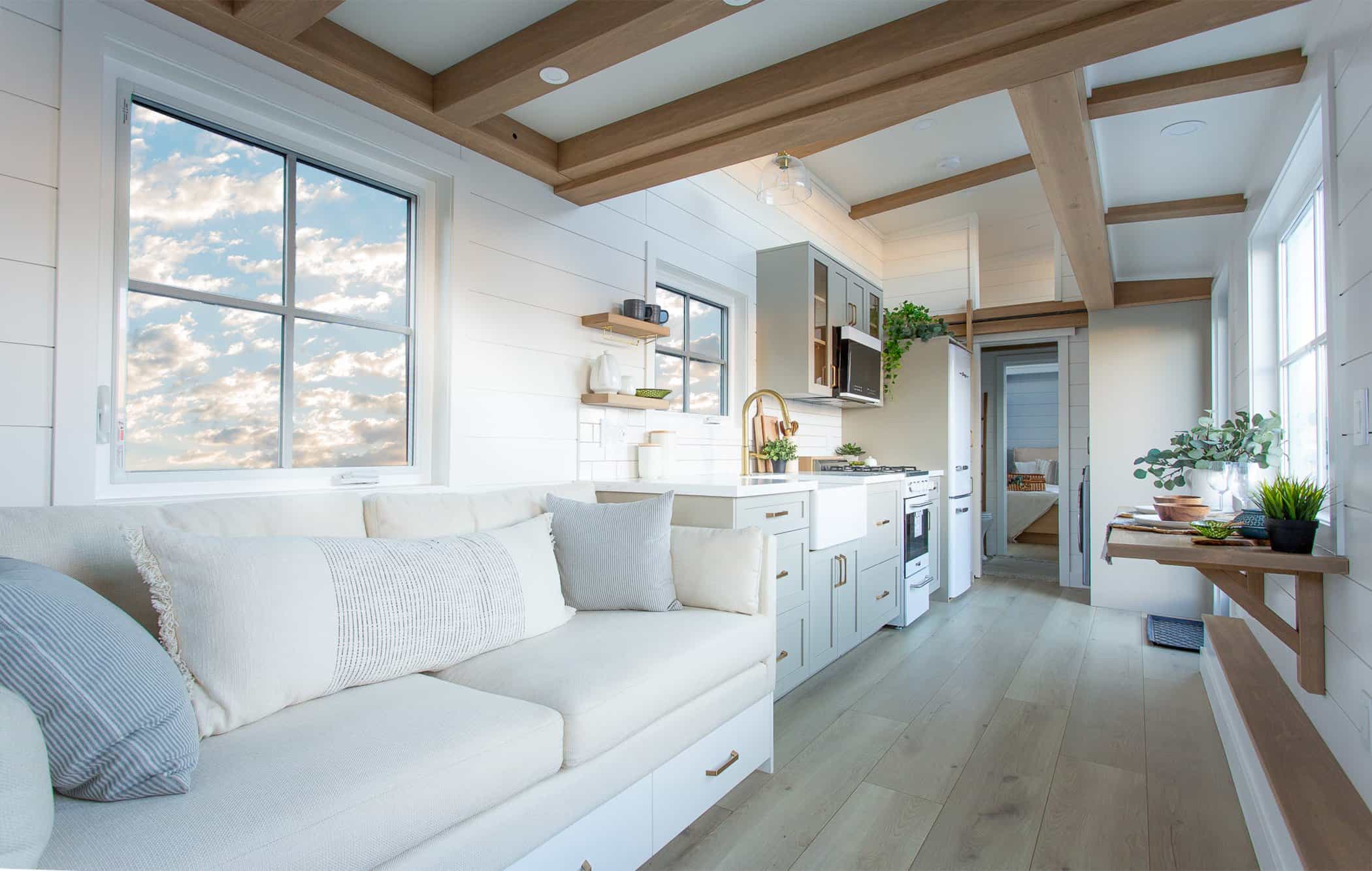 Summit Boho living toward kitchen and bedroom: white shiplap, wood beams, open length of the house
