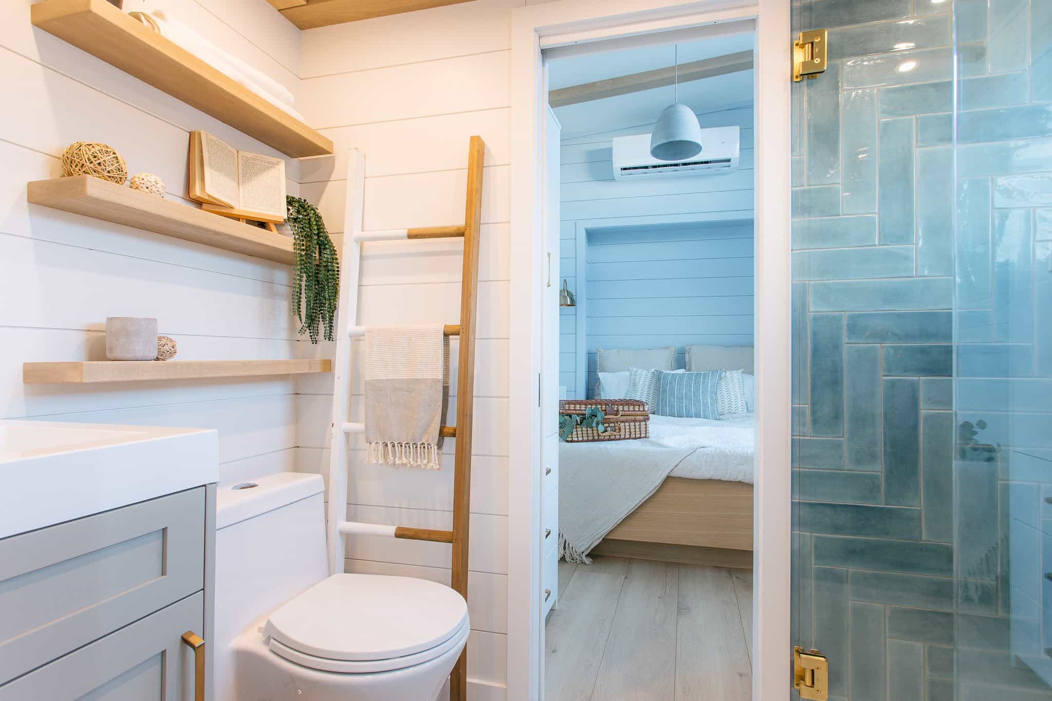 Summit Boho passthrough bathroom toward bedroom: vanity, flush toilet, tub-shower with teal herringbone tile, gold hardware, bedroom beyond