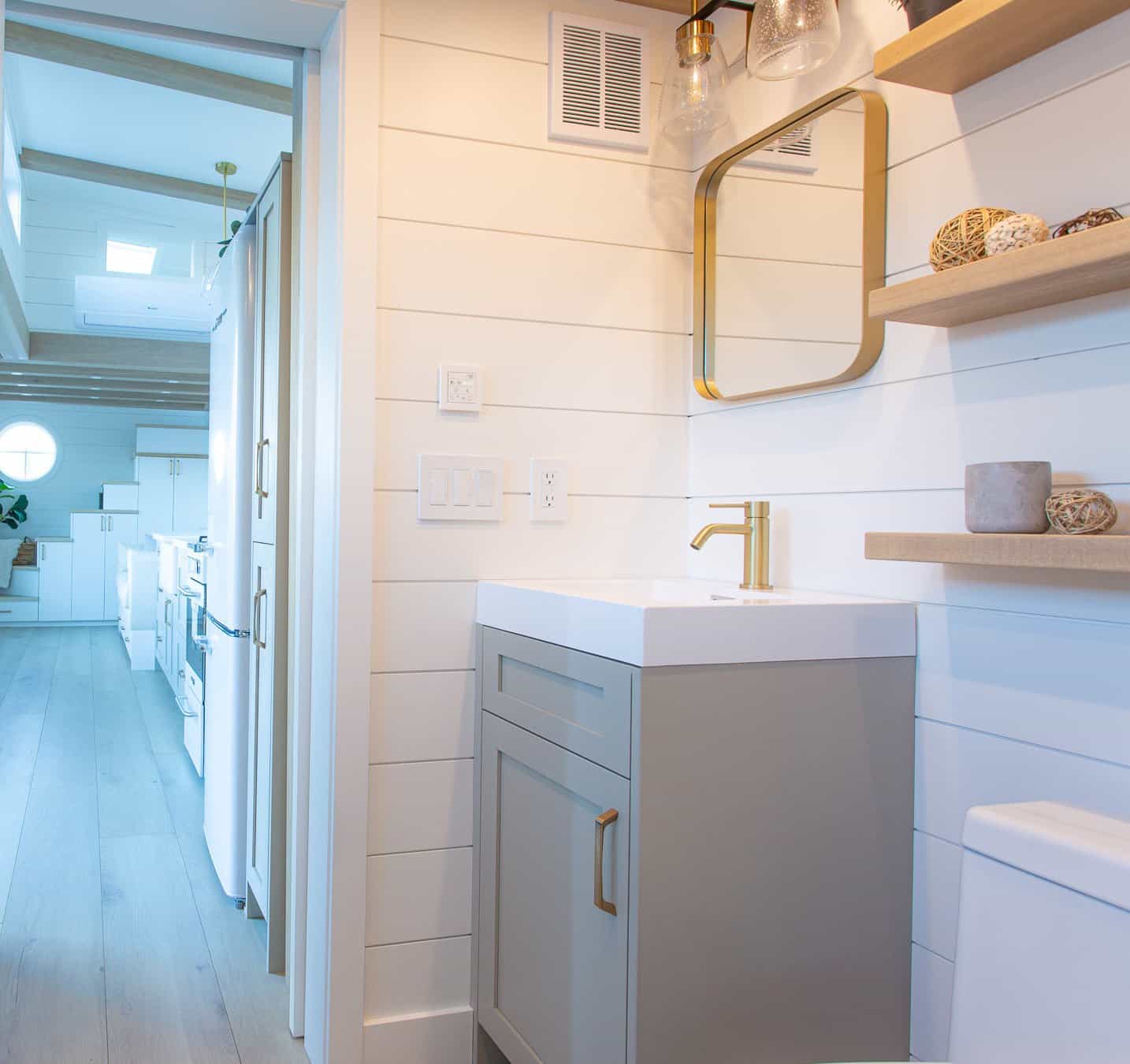 Summit Boho vanity and bath looking into living: wood shelves, white shiplap, warm finishes