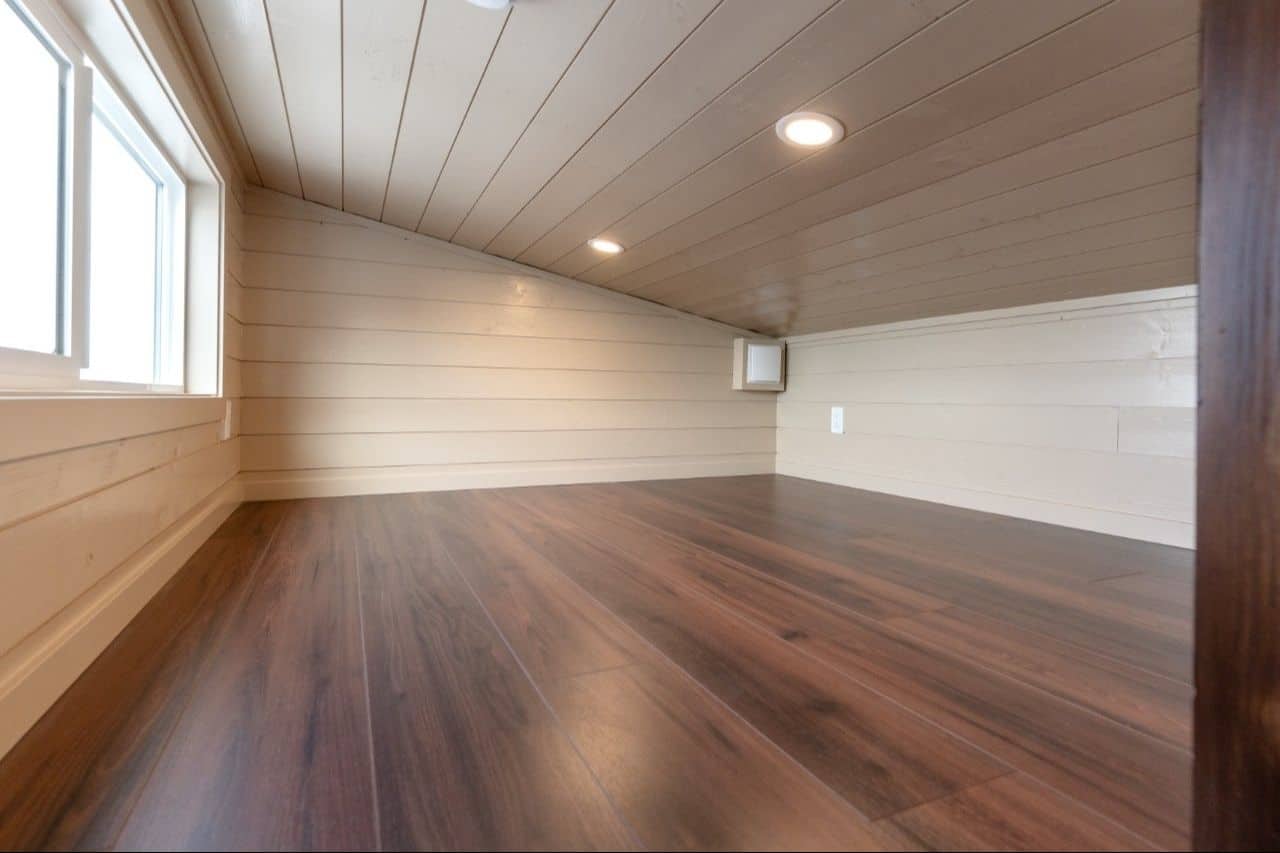 2026 Ruby loft interior: pitched cream shiplap, dark plank floor, large side slider, two recessed lights, outlet on the end wall