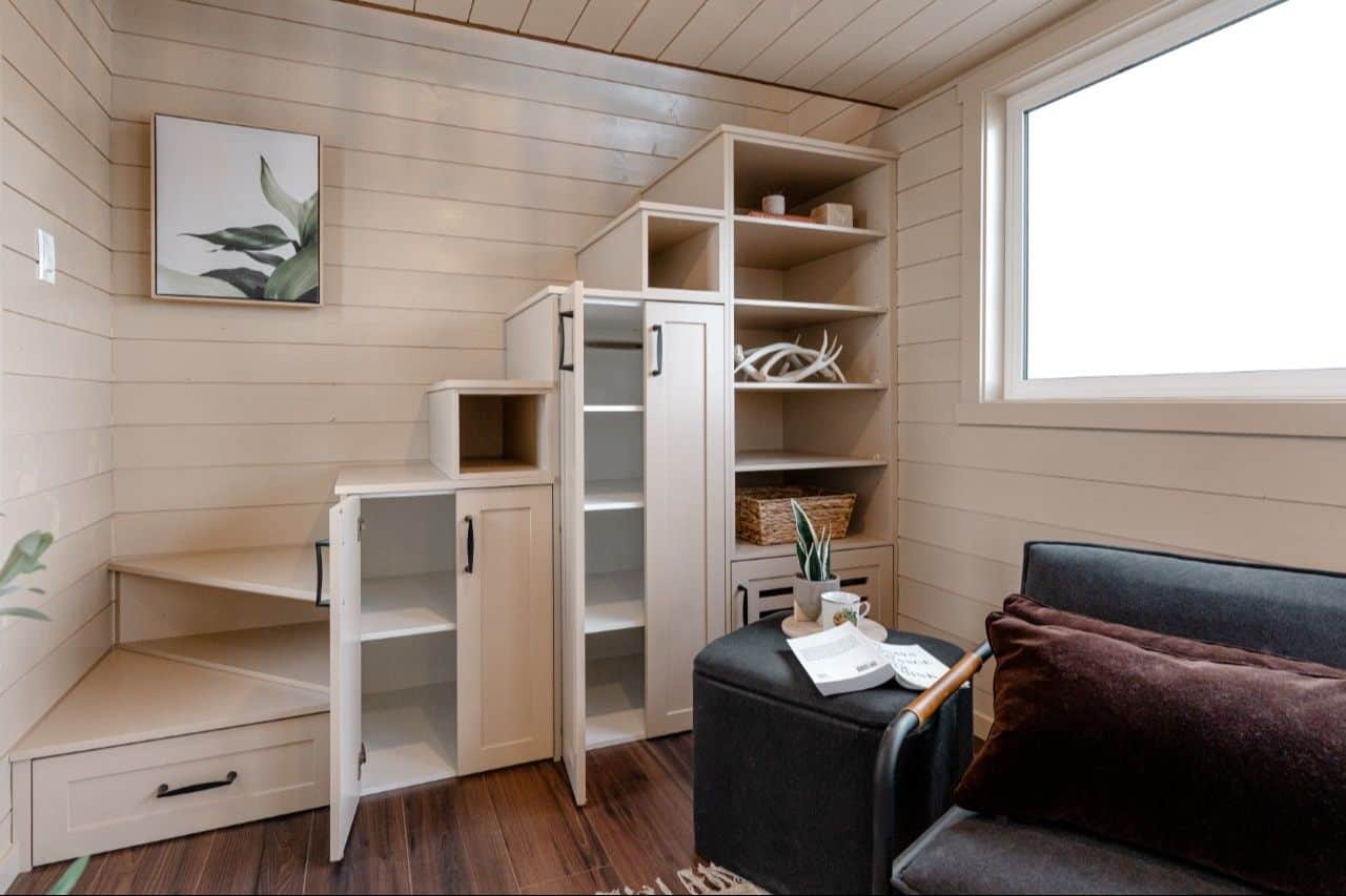 Close on the 2026 Ruby white storage staircase: base drawer, open cabinet doors, cubbies in the treads, tall open shelves