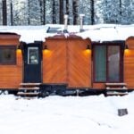 Tiny house with wooden exterior in a snowy landscape.