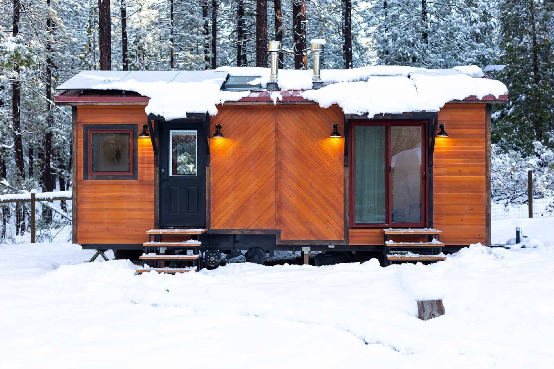 Tiny house with wooden exterior in a snowy landscape.