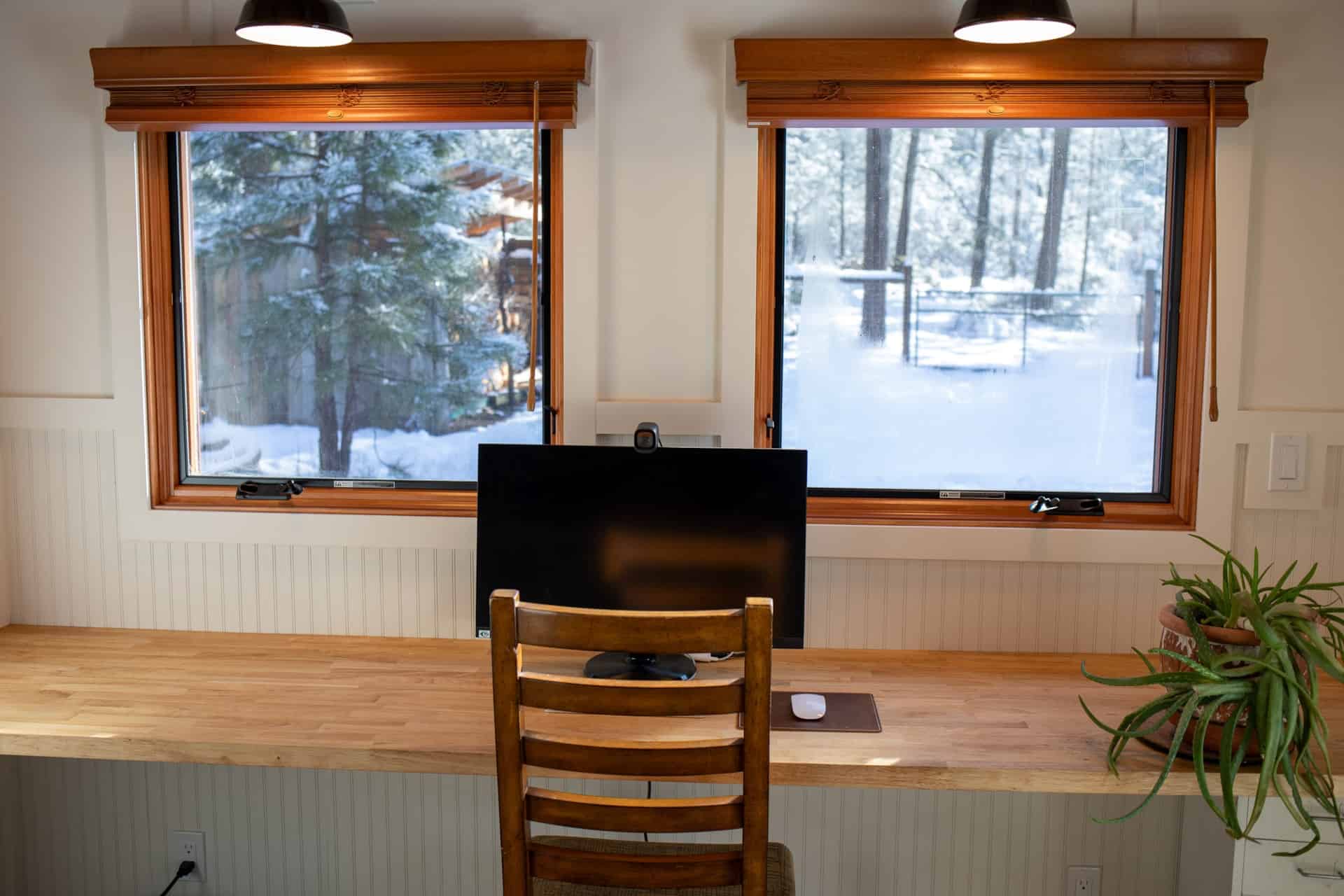 Bright tiny house office with large windows overlooking snowy woods.
