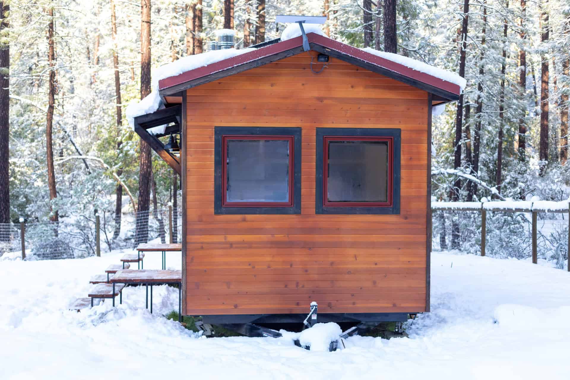 Tiny house cabin in a snowy forest setting, showcasing compact living in nature.