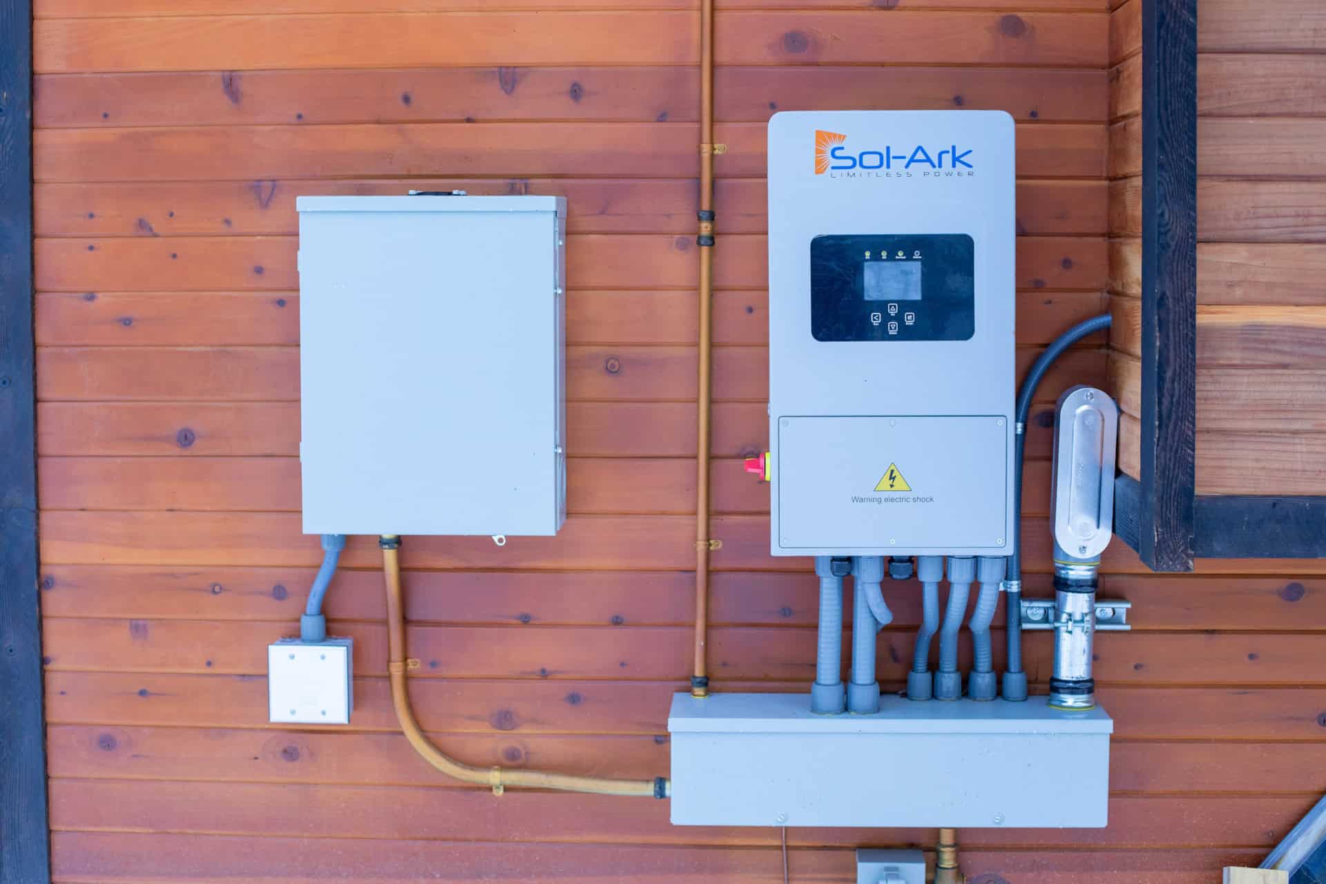Solar power system with Sol-Ark inverter on wooden wall.
