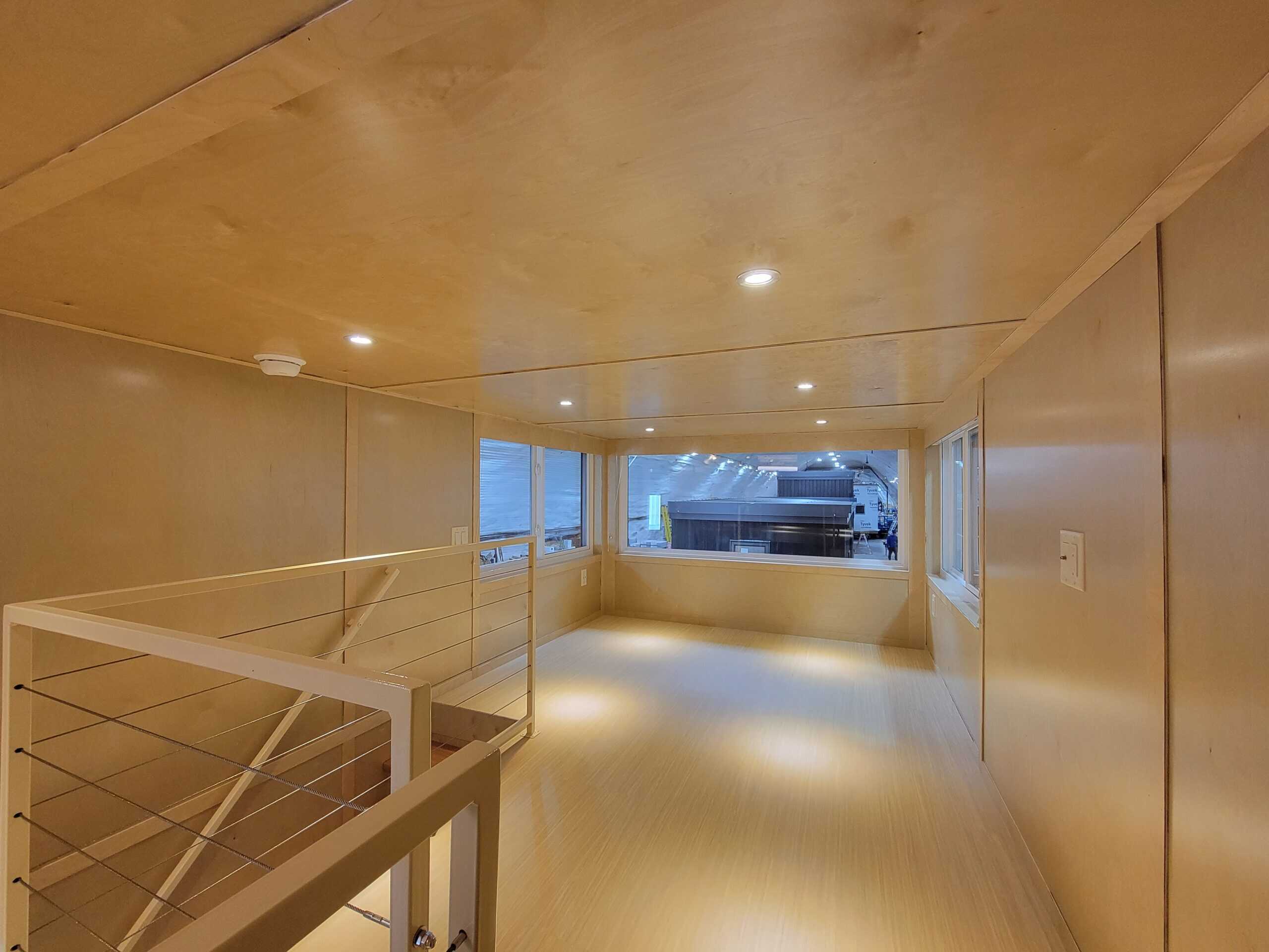 Bright tiny house interior with large windows and minimalist wooden design.