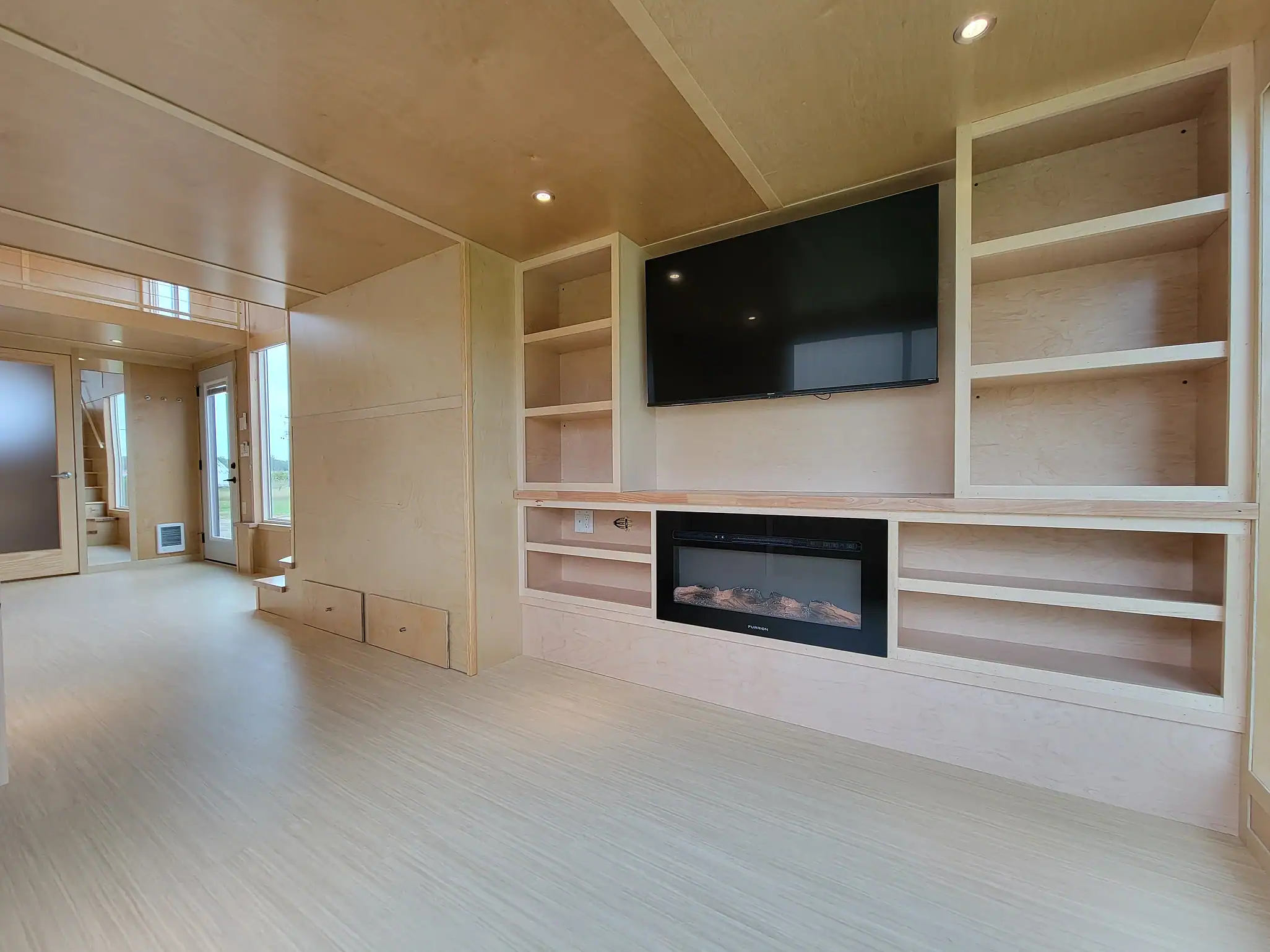 Modern tiny house living room with built-in shelves and a sleek fireplace.