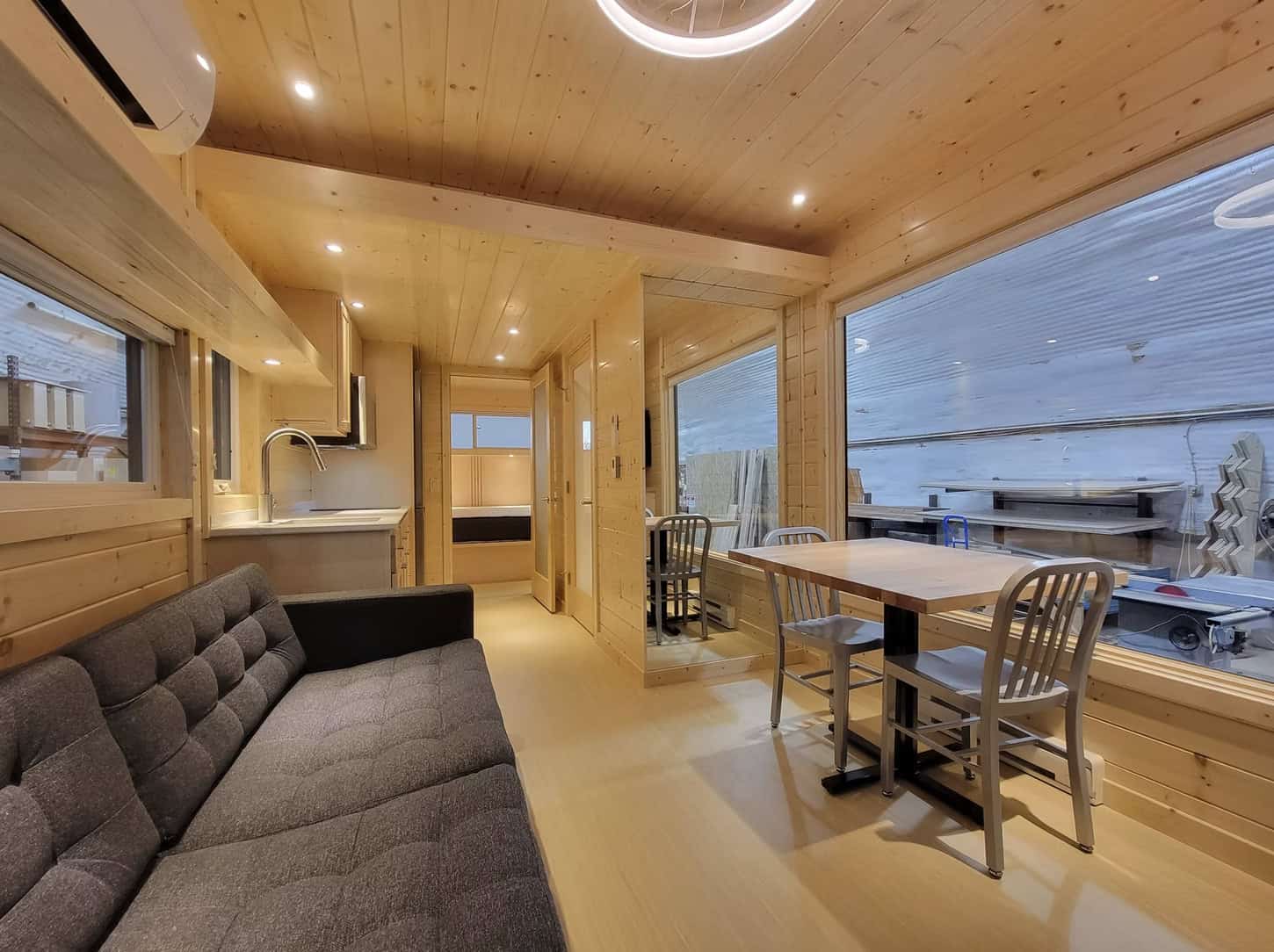 Interior of a modern tiny house with wooden walls and large windows.