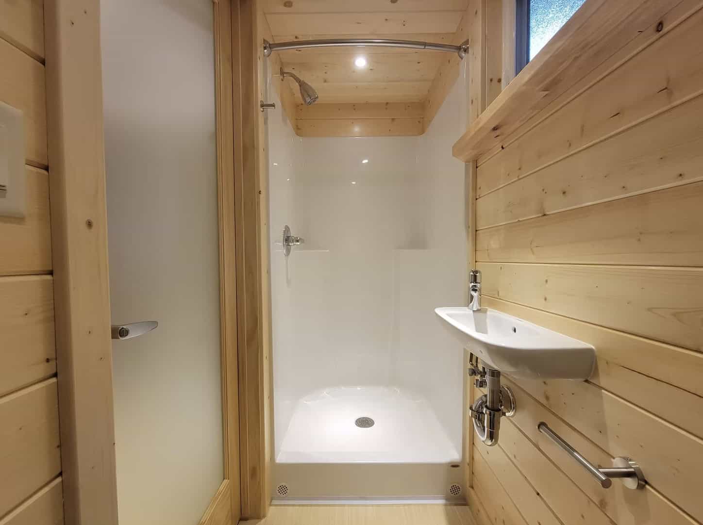 Small bathroom with wooden walls and a compact shower area.