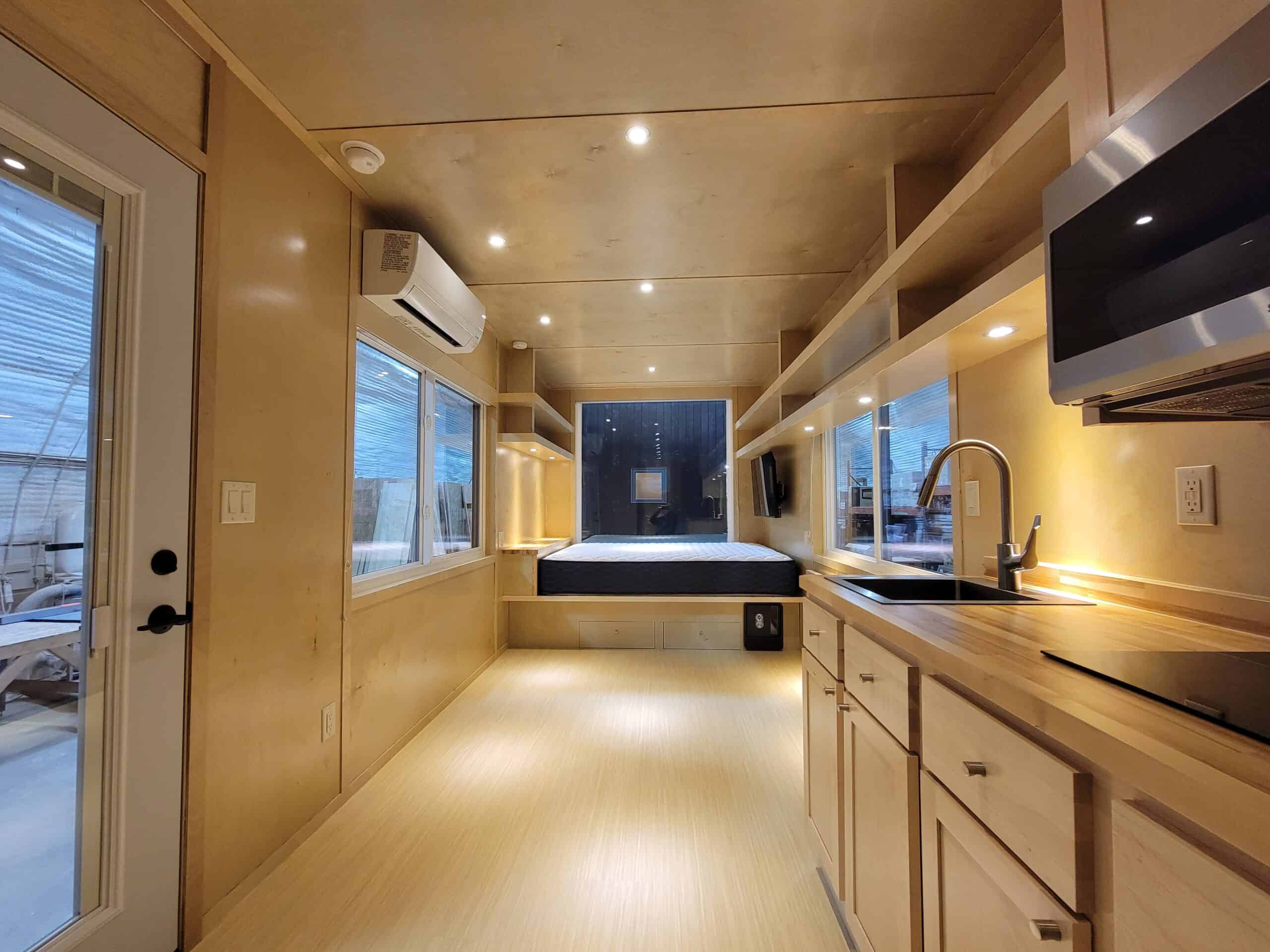 Modern tiny house interior with compact kitchen and cozy sleeping area.