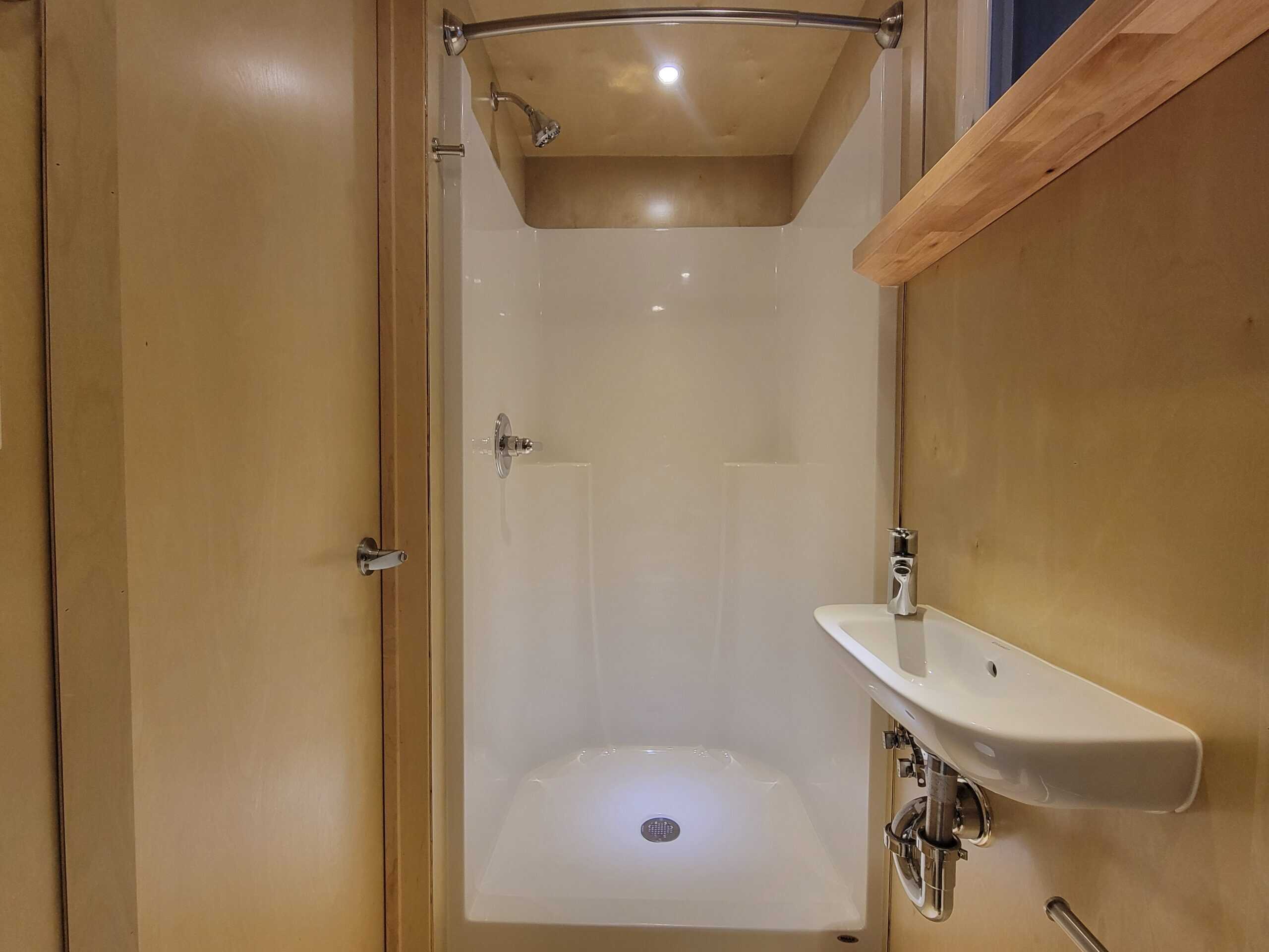 Shower and small sink in a compact tiny house bathroom.