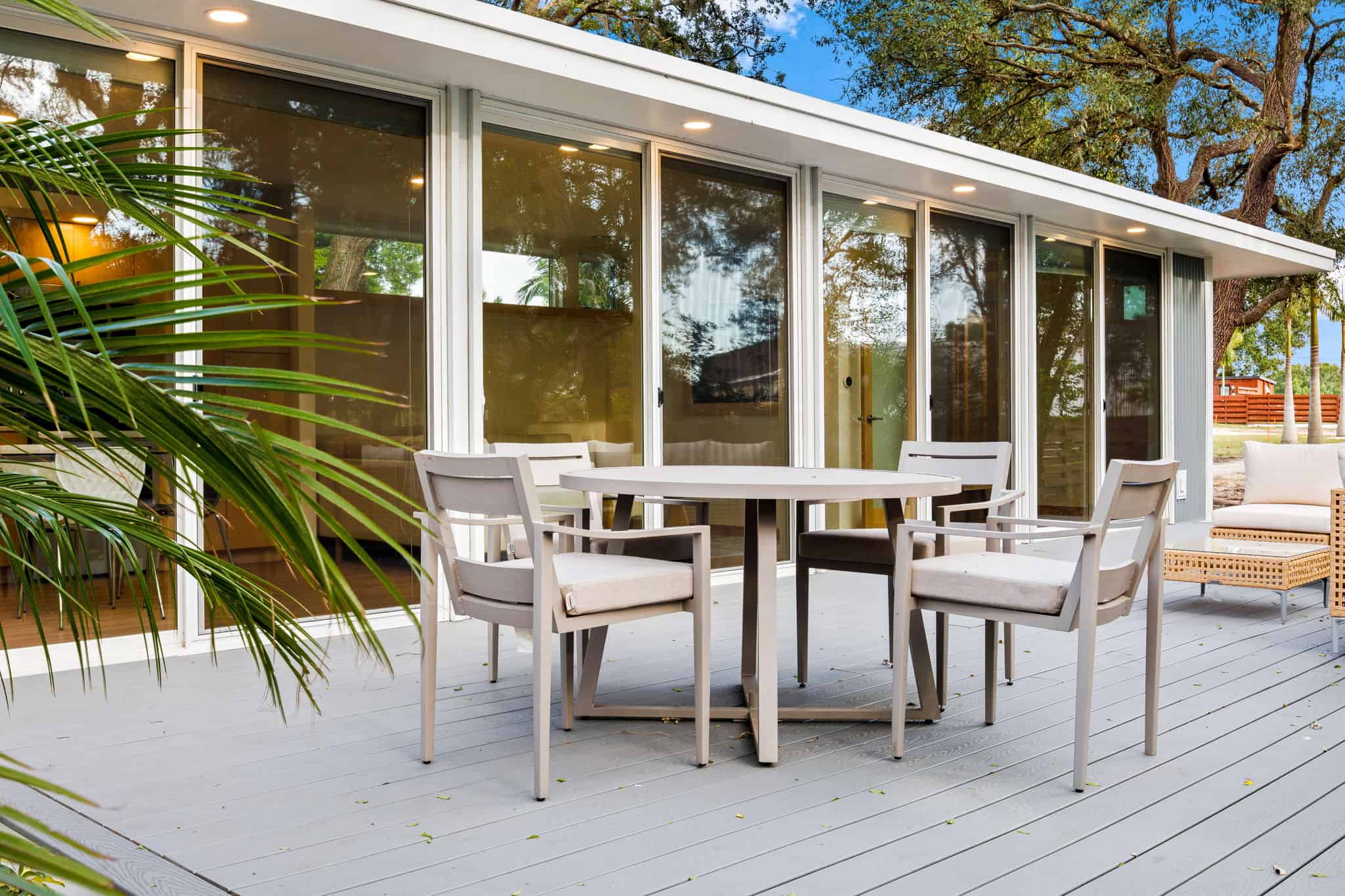 Modern tiny house with large glass windows and outdoor patio area.