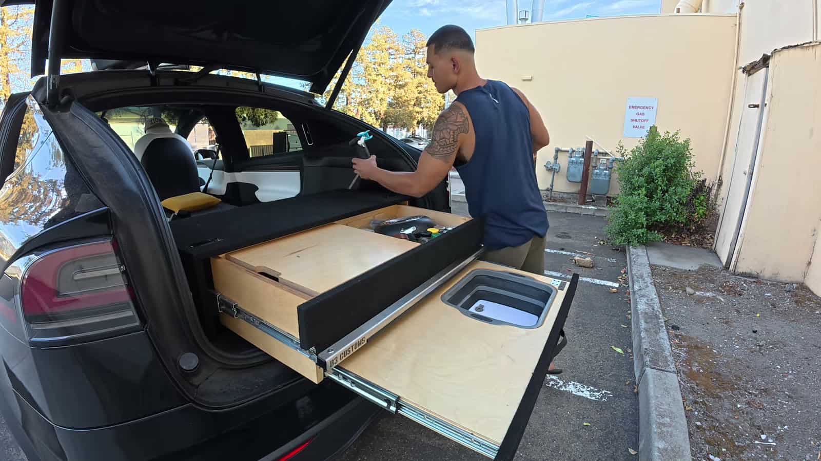 Slide-out plywood kitchen drawers with a sink basin at the rear of a Tesla Model X