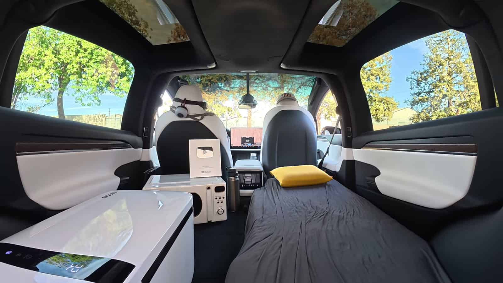 Interior of a converted Tesla Model X with a full-length bed and glass roof