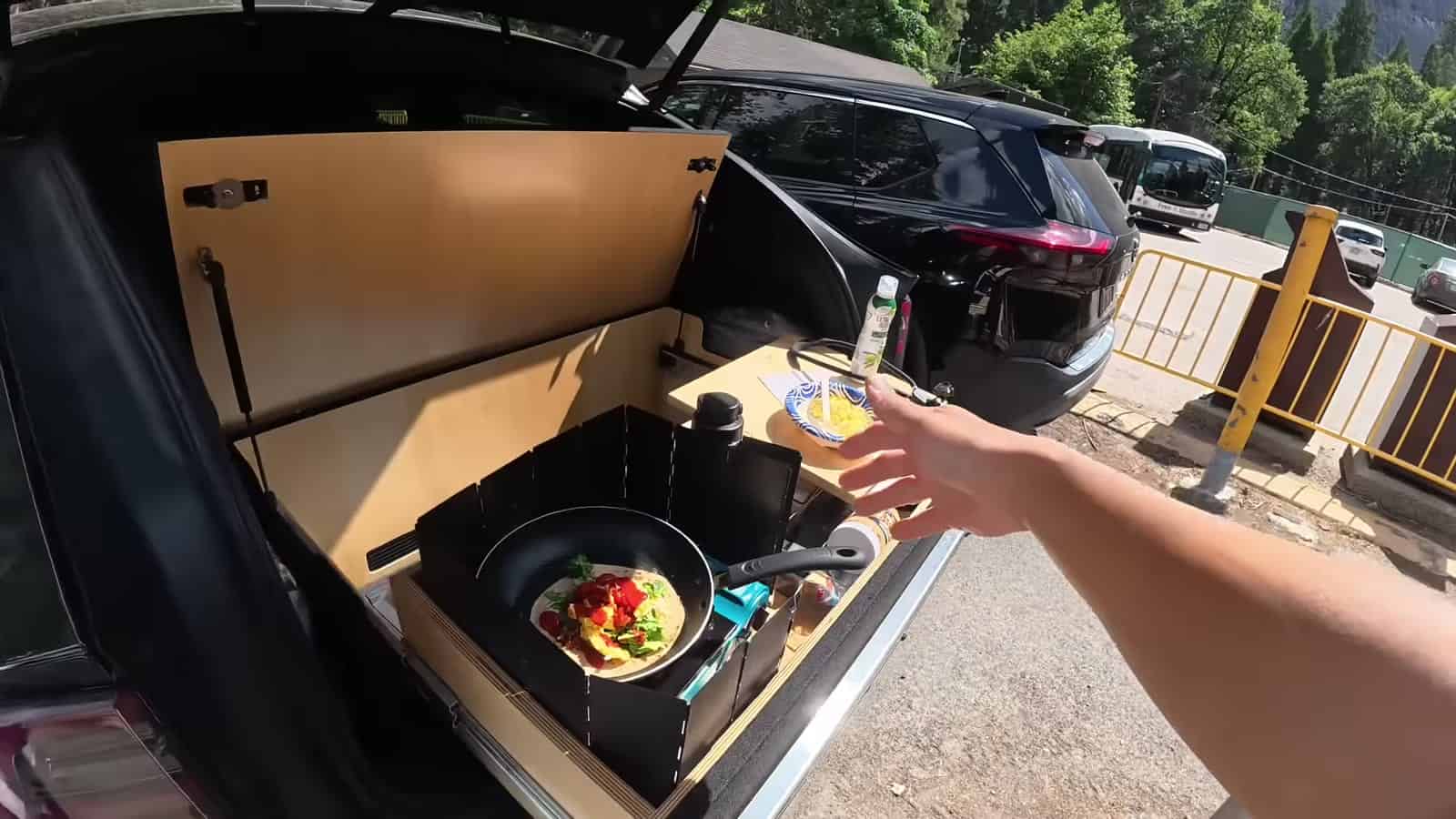 Cooking eggs on a camp stove in the tailgate kitchen of a Tesla at Yosemite