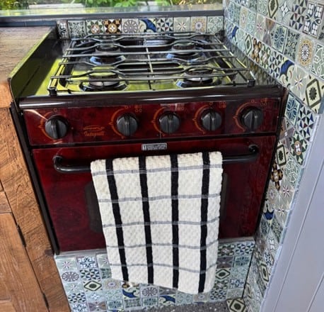 Red gas cooker with four burners set in patterned tile