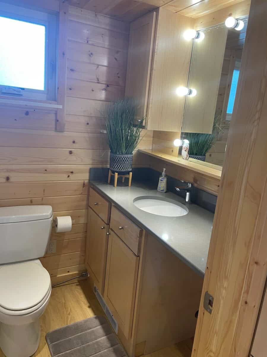 Compact bathroom with wooden accents and modern lighting in a small vacation cottage.