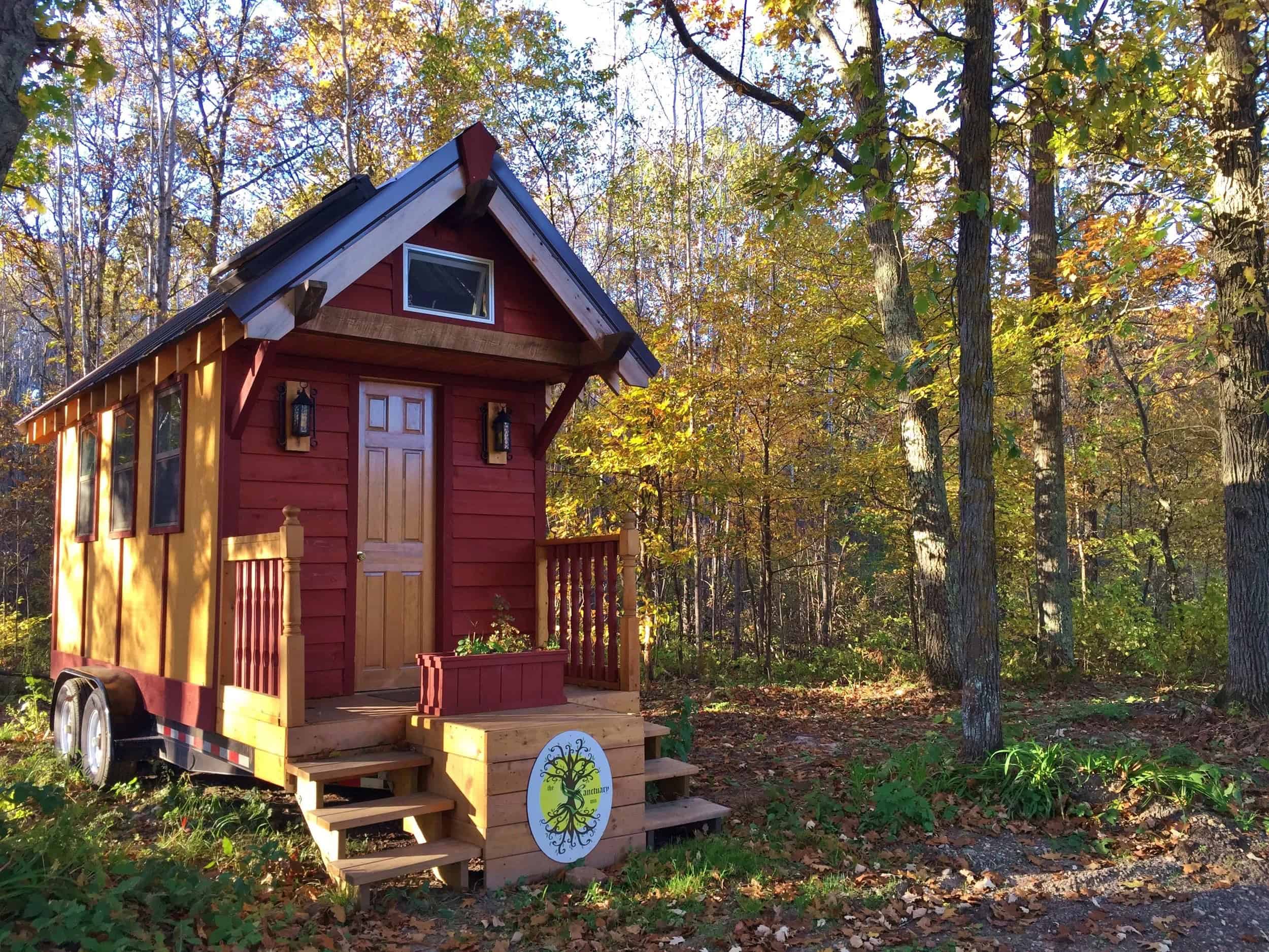 Tiny house on wheels parked in a wooded clearing at The Sanctuary Minnesota village in Ogilvie, Minnesota