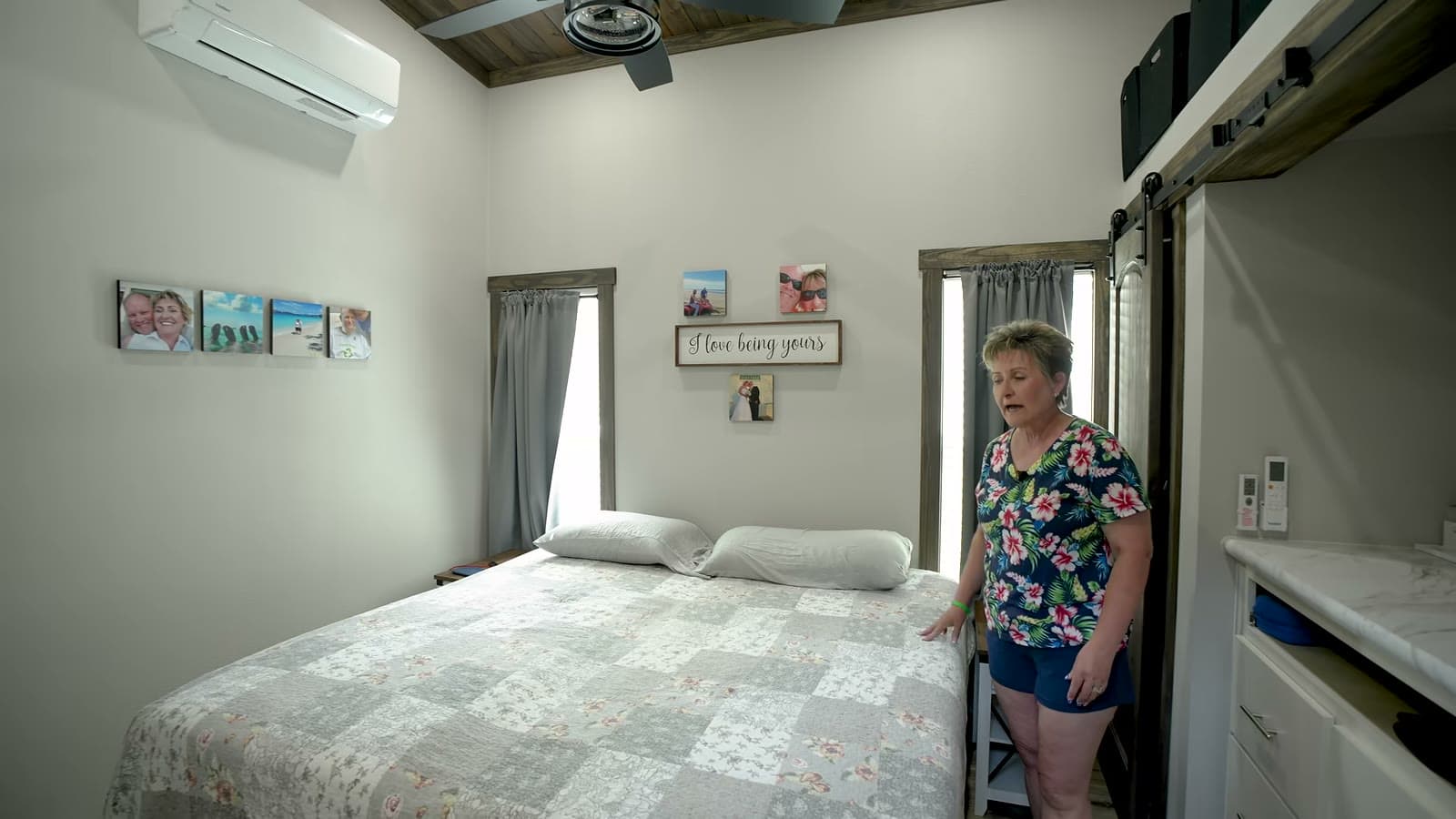 Park model bedroom with king bed, patchwork quilt, family photos, mini-split and sliding barn-style closet doors