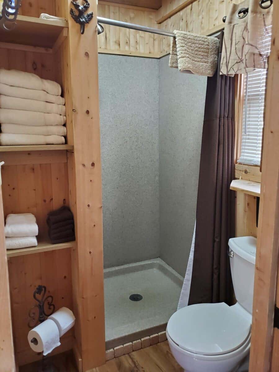Treehouse bathroom with a shower stall, toilet, and towel shelves