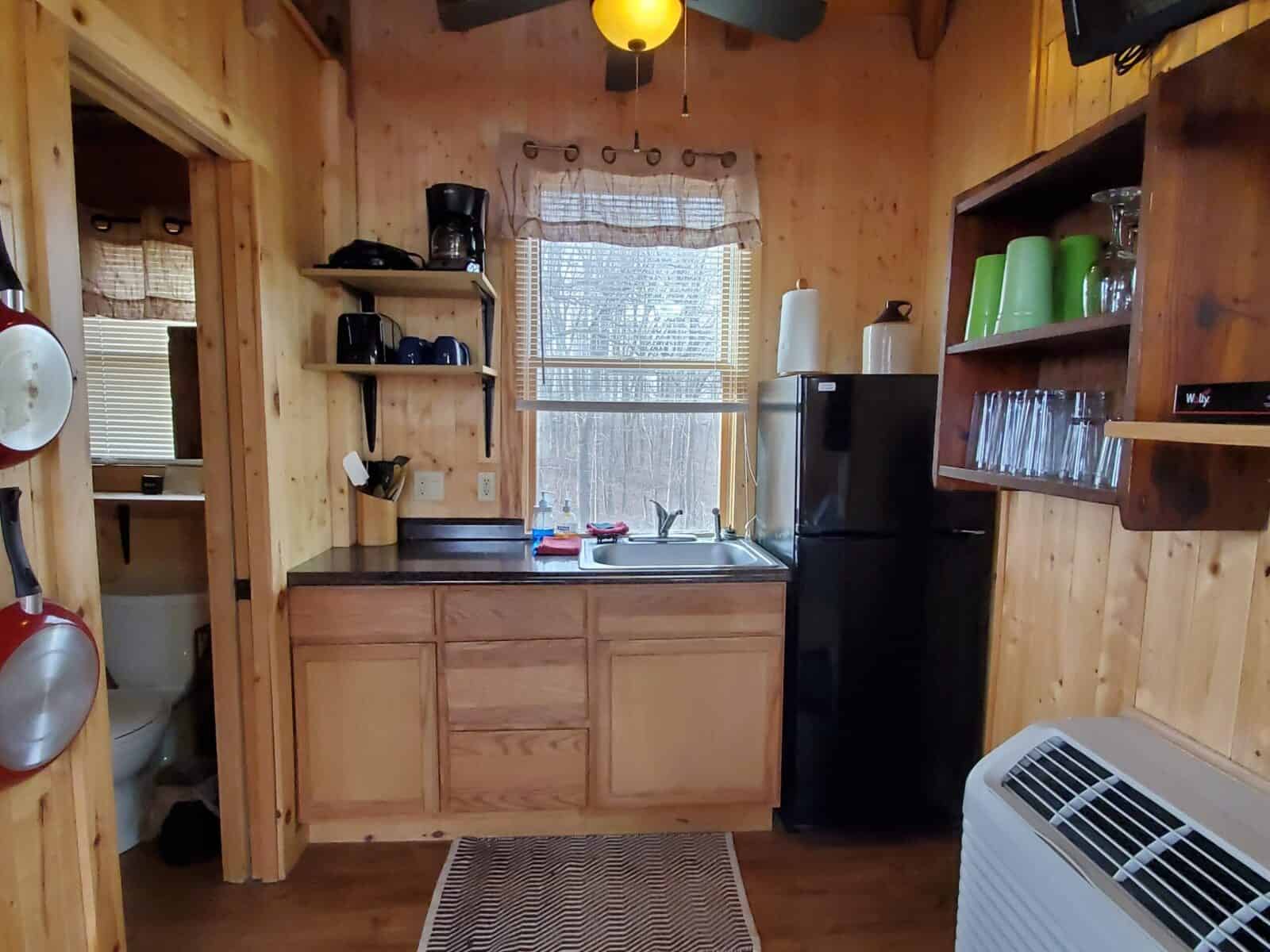 Kitchenette inside the White Oak Treehouse with a sink, refrigerator, and open shelves