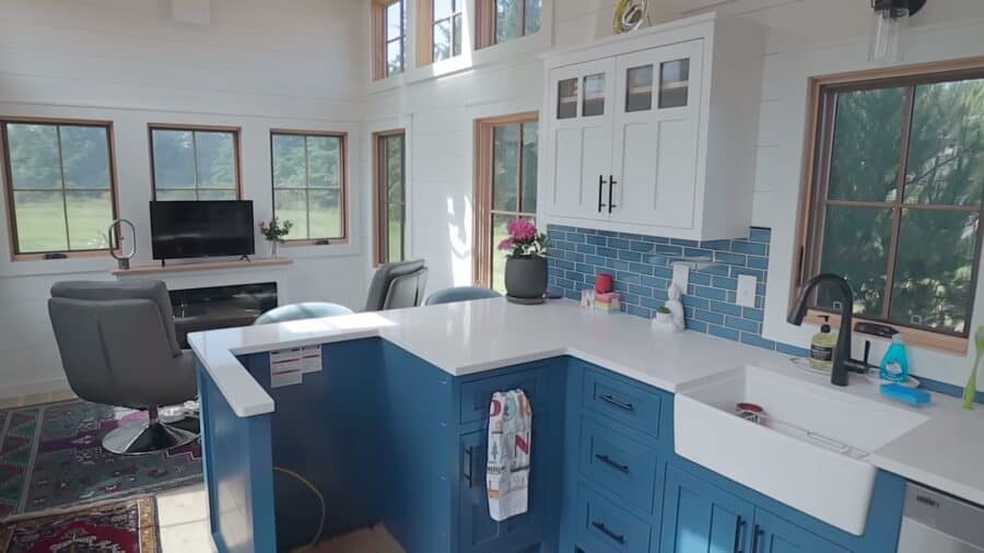 L-shaped kitchen with blue cabinets, quartz counters and a desk nook in the Timbercraft tiny home
