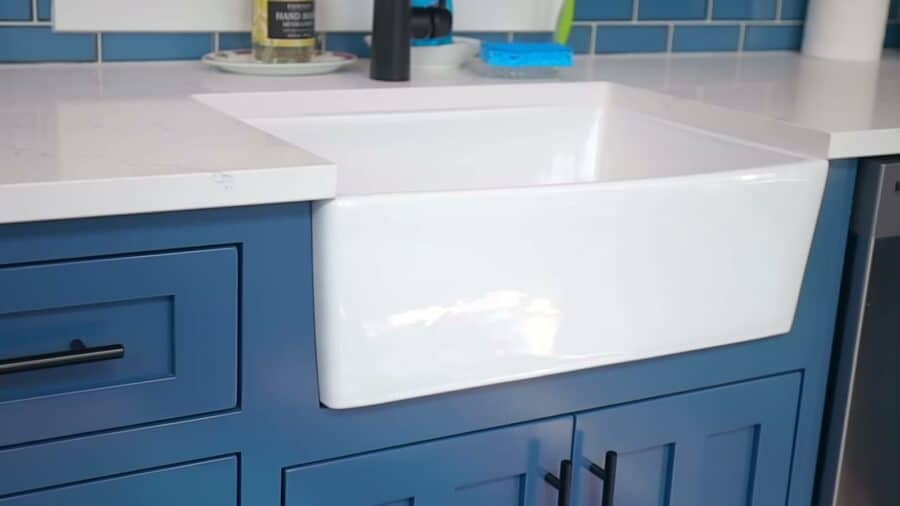 White farmhouse sink set into custom blue shaker cabinetry