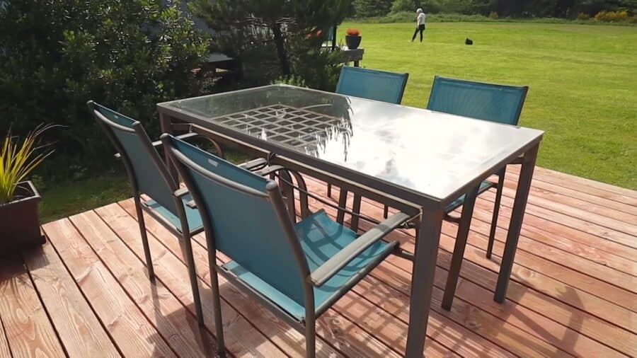 Wood deck with a glass patio table and blue chairs overlooking the meadow