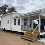 Tiny house with a spacious deck and modern design, perfect for small space living and outdoor relaxa.