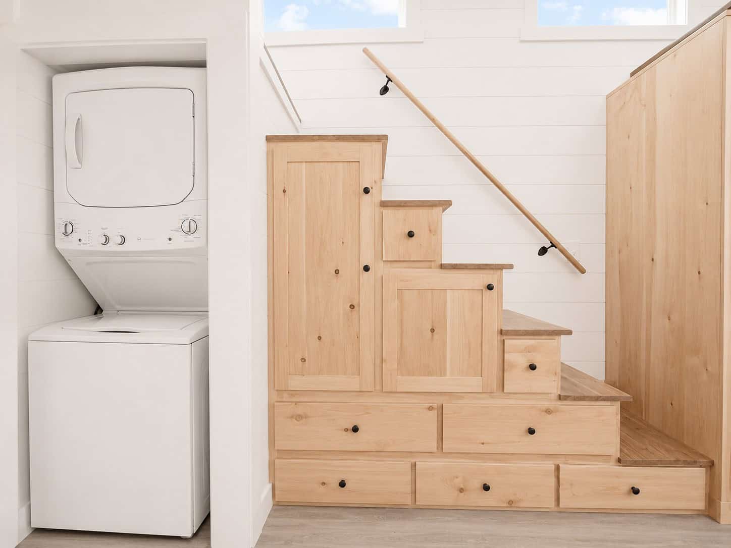 Wood stairs with drawers and cabinet doors, and a stacked washer and dryer in a closet at left