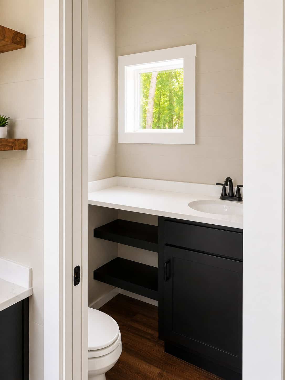 Bathroom with a white counter, black faucet, open black shelves, a dark cabinet, and a toilet