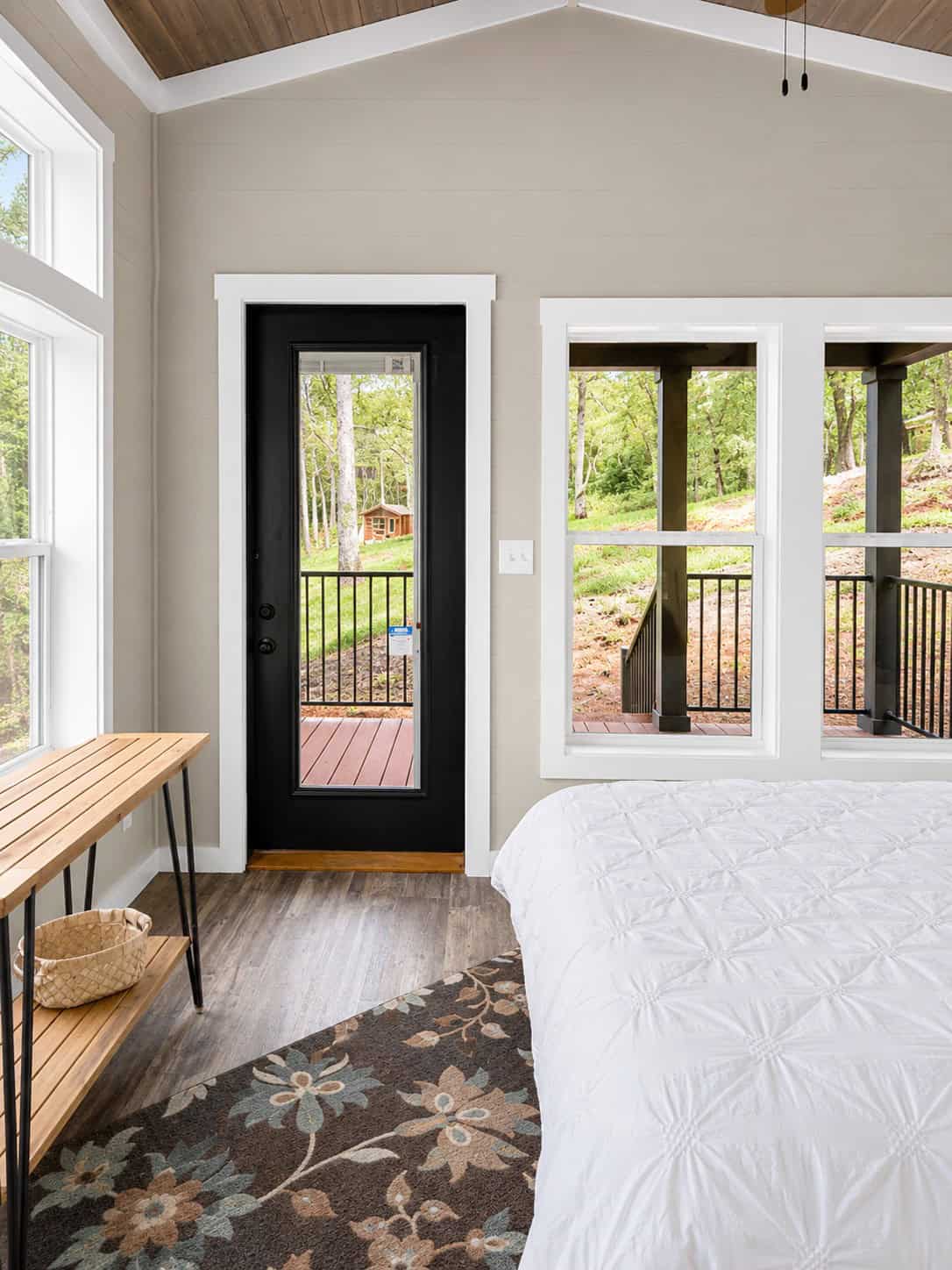 Bedroom with a black door and double windows looking onto a covered deck