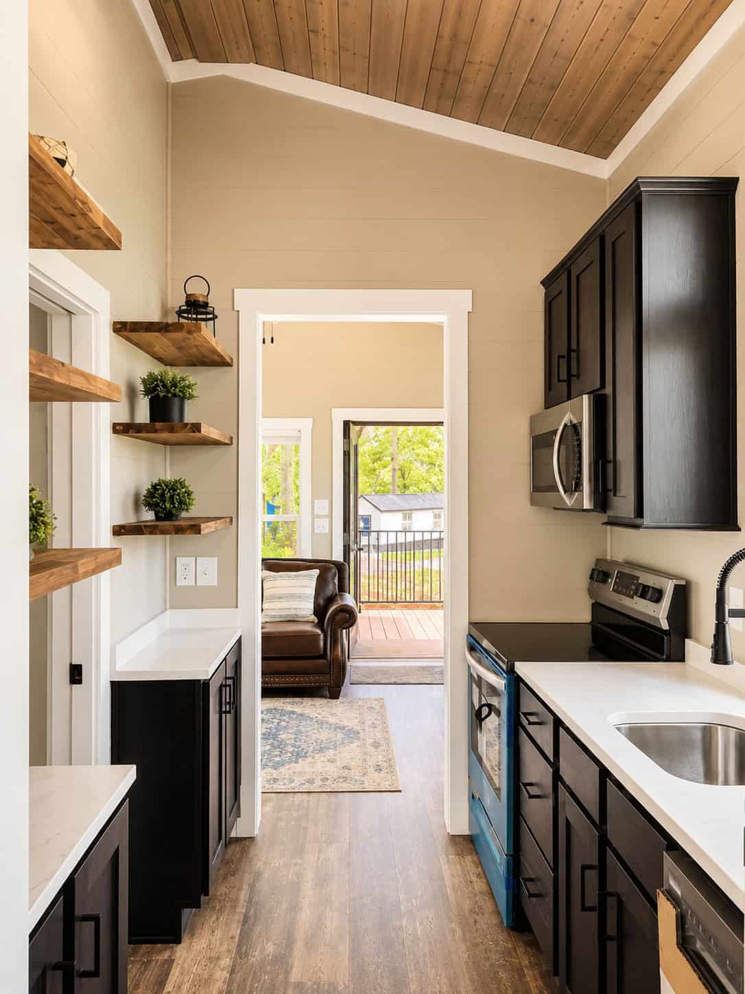 Galley with a stainless range and microwave, dark cabinets, and a view through to a leather chair and a deck