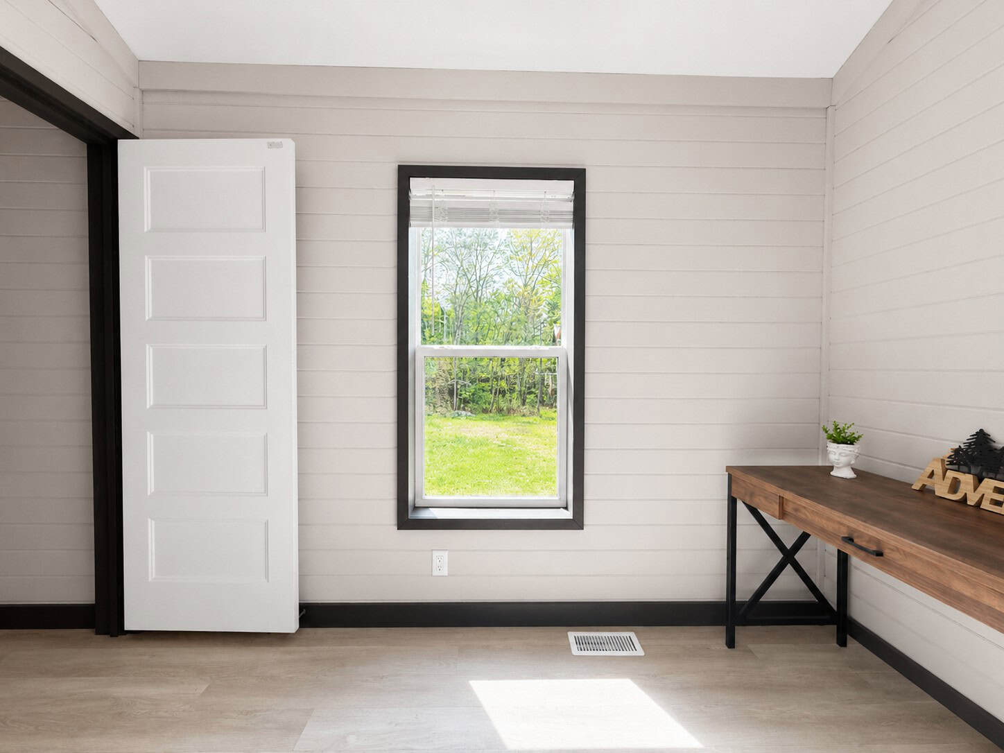 Bedroom wall with a window, a wood desk, and a white door