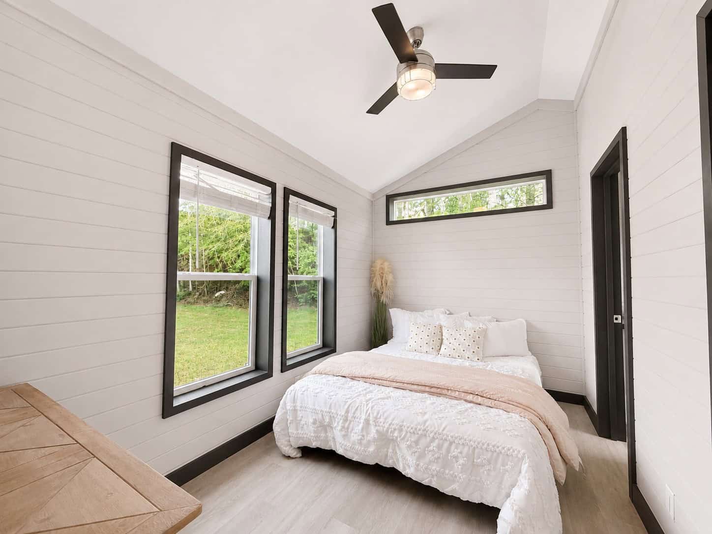 Bedroom with a bed, ceiling fan, two windows, and a high window