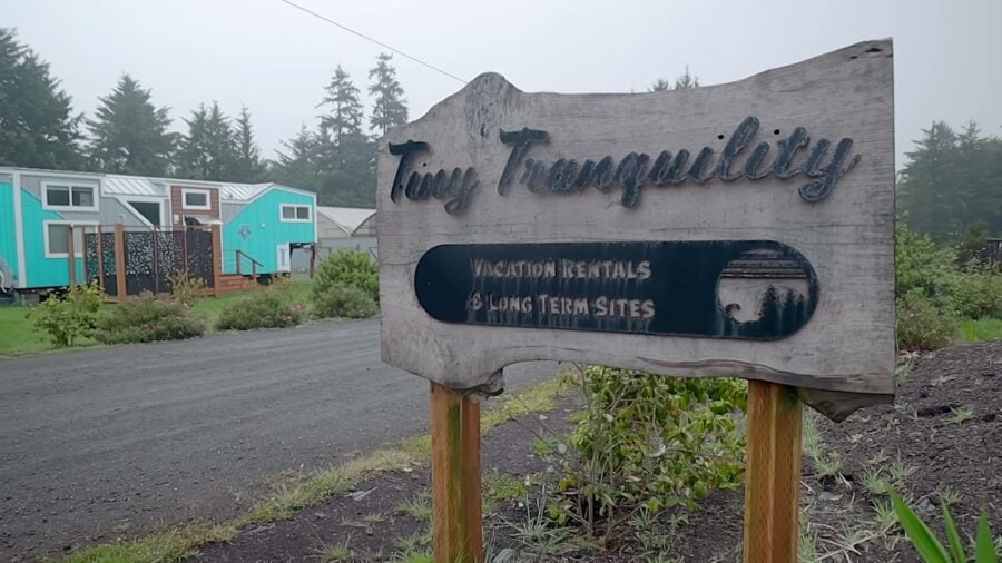 Tiny Tranquility sign with tiny homes in the park behind it