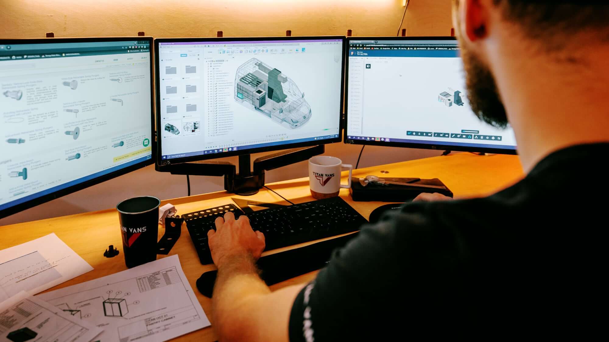 Designer at Titan Vans working a three-monitor layout of a camper van interior