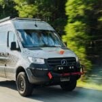 Silver Titan Vans Mercedes Sprinter camper conversion driving a forest road, roof rack and front guard visible