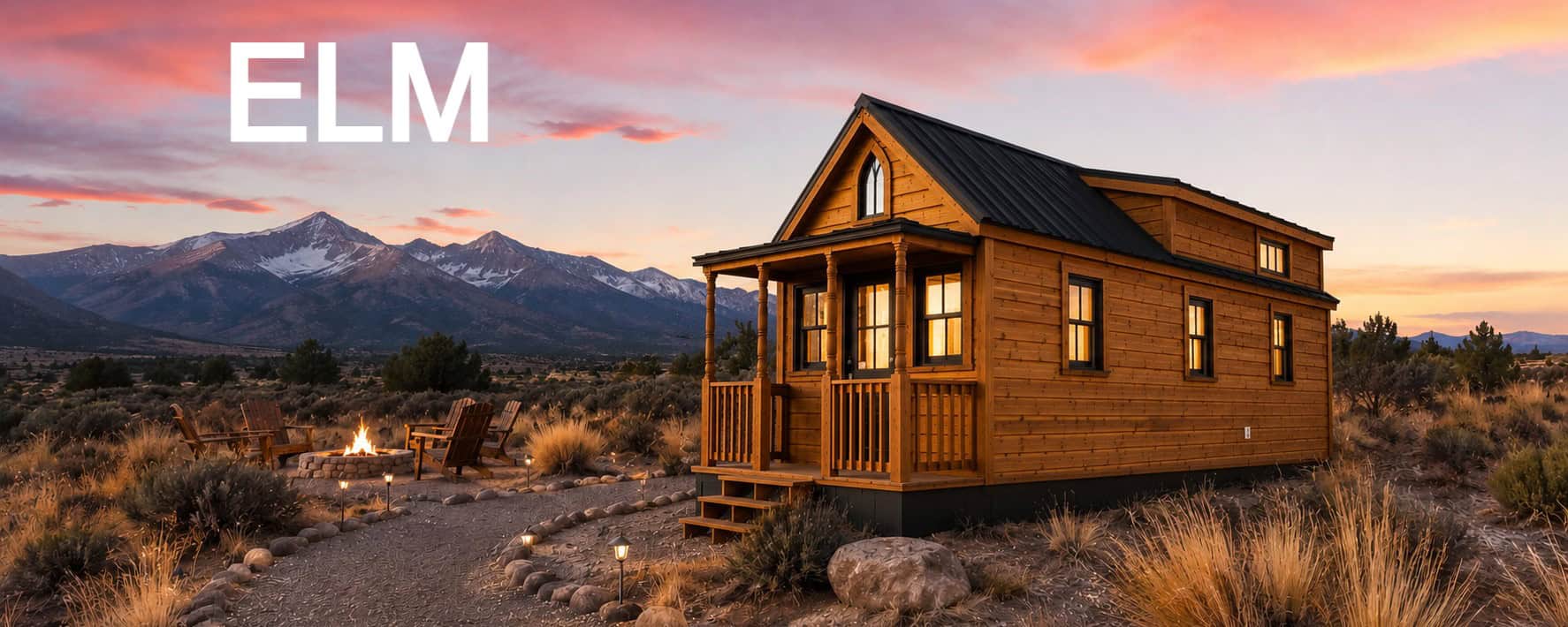 Honey-cedar Tumbleweed Elm on a trailer at dusk: gothic-arch window over a covered porch with turned posts, stone fire pit and Adirondack chairs, snow-capped mountains, ELM wordmark