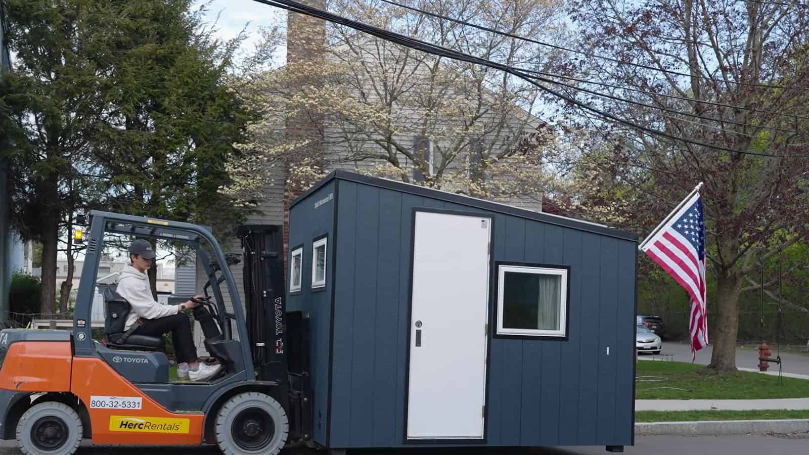 Uplift Micro Home being carried down a residential street on a standard forklift