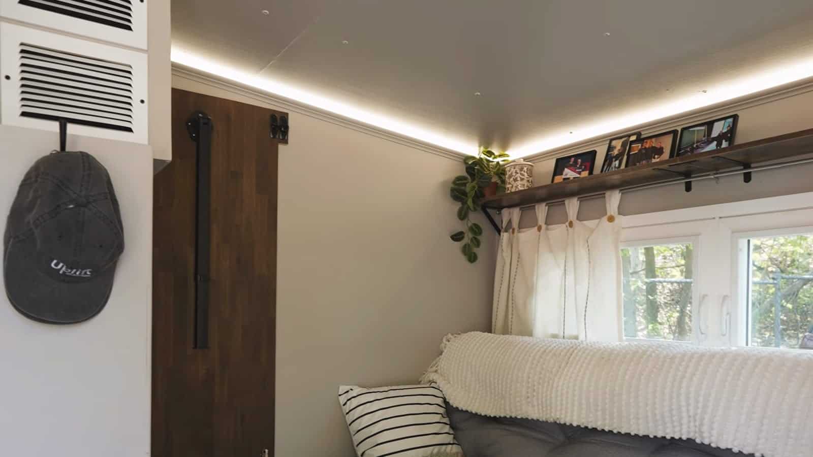 Interior of the Uplift Micro Home showing the full-size bed, window and cove lighting
