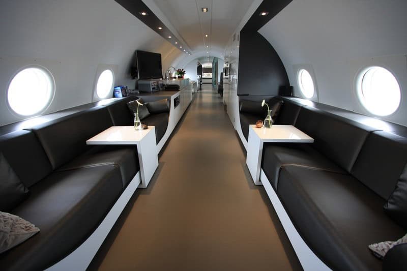 Full cabin looking from the cockpit end toward the bedroom: dual sofas, pantry with oven and microwave, aisle to the bed